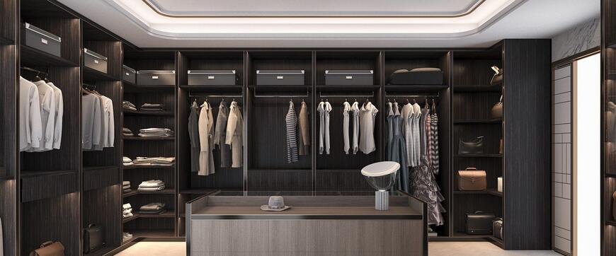 Spacious walk-in closet with dark wood finish, featuring neatly hung clothes, shelves with folded items, storage boxes, and a central island with a mirror and hat—an elegant blend of modular wardrobe design.